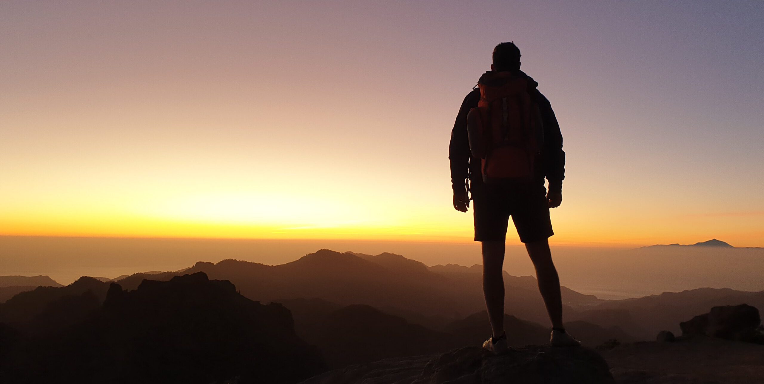 Wanderer auf dem Gipfel des Berges blickt in den Sonnenuntergang